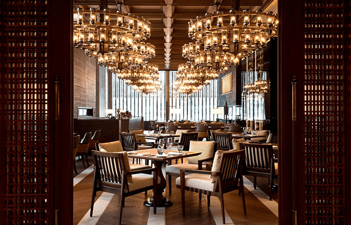 The restaurant of the luxury ski hotel the Chedi Andermatt hotel with brown tables and chairs and chandeliers
