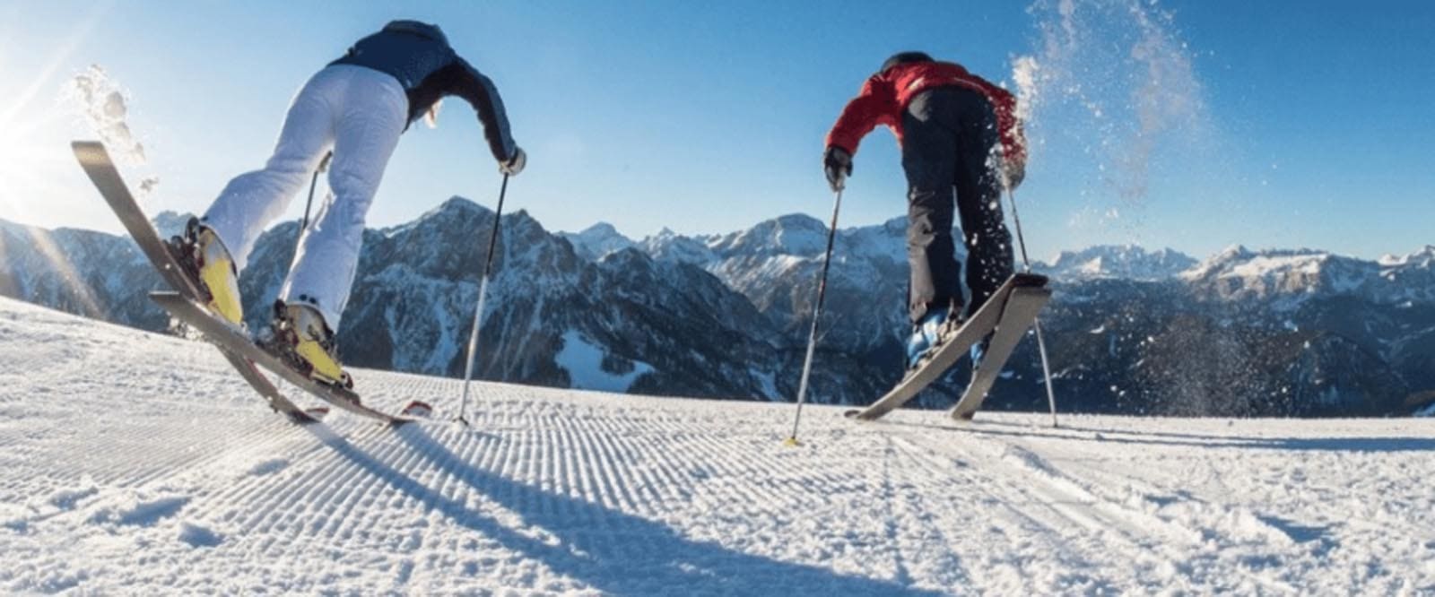 Two skiers pushing off down a ski slope in the Italian Alps
